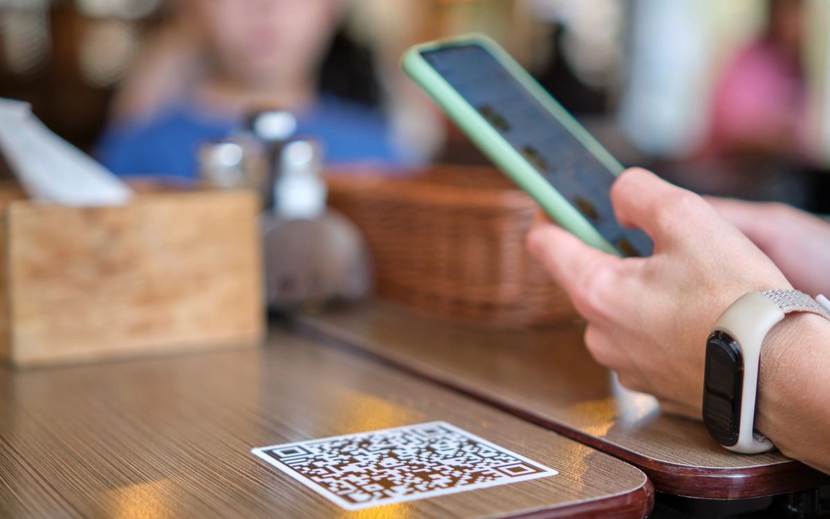 A customer scanning a menyu QR code on a restaurant table to order from their phone